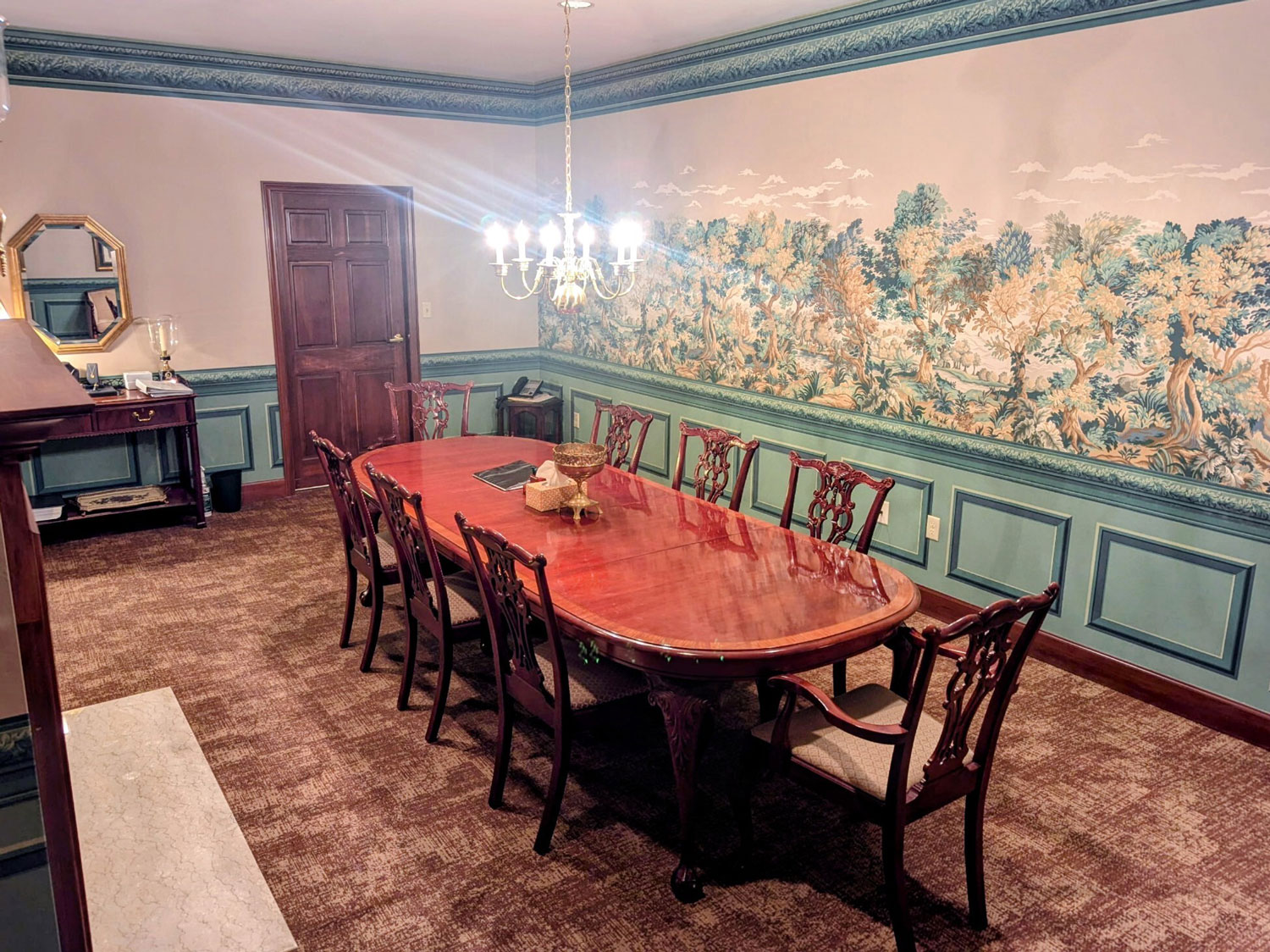 The arrangement room featuring an elegant wooden table and chairs with a low-hanging chandelier.